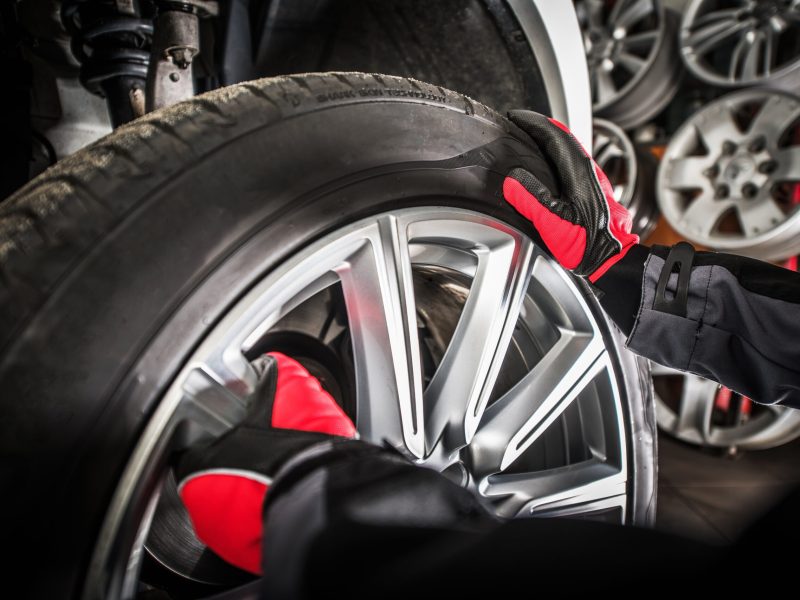 Balancing Vehicle Wheels. Modern Car in the Auto Service. Professional Worker Removing Wheel From the Car.
